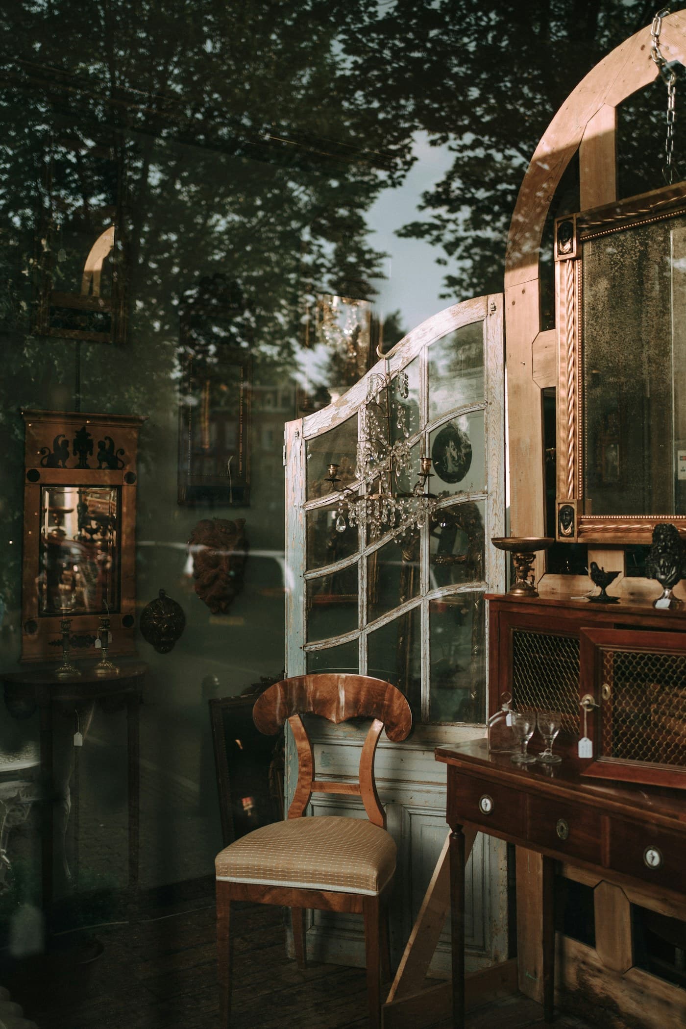 Vintage furniture, mirrors, and lighting arranged in an antique shop